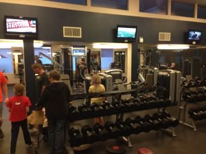 A fitness room with people and children working out