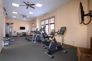 A fitness equipment room with fans above