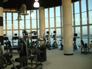 A fitness equipment room overlooking a lake and city