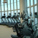 A curved windowed area with ellipticals treadmills and bikes lined up against it