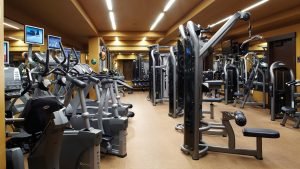 A row of ellipticals and bikes with strength equipment to the right