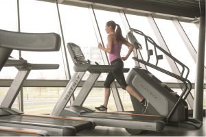 A woman in a pink shirt running on a Matrix Treadmill