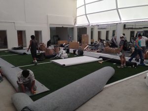 People laying out a fake field in a fitness center