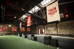 A large indoor fitness center with fake grass and signs for Train Chicago