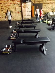 4 weight benches in a room with people walking around