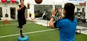 Two people standing on special balls throwing a basketball back and forth