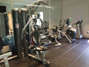 A tiled fitness room with weights and cardio machines