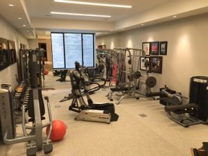 A fitness room with a mirror on one wall and a window on the other