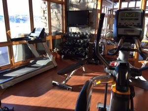 A fitness room with a window facing a snowy mountain