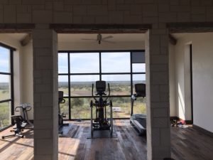 A windowed room with an elliptical, bike, and treadmill