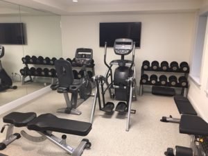 A TV sits behind a residential elliptical in a fitness room