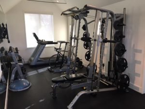 A treadmill and bike with weight training equipment in a small room