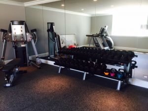 A mirrored room with weights and a weight machine