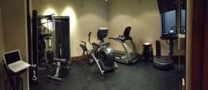 A smaller fitness room with a laptop and residential fitness equipment