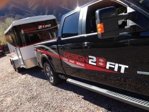 A truck and a trailer with the logo for Design 2 B Fit